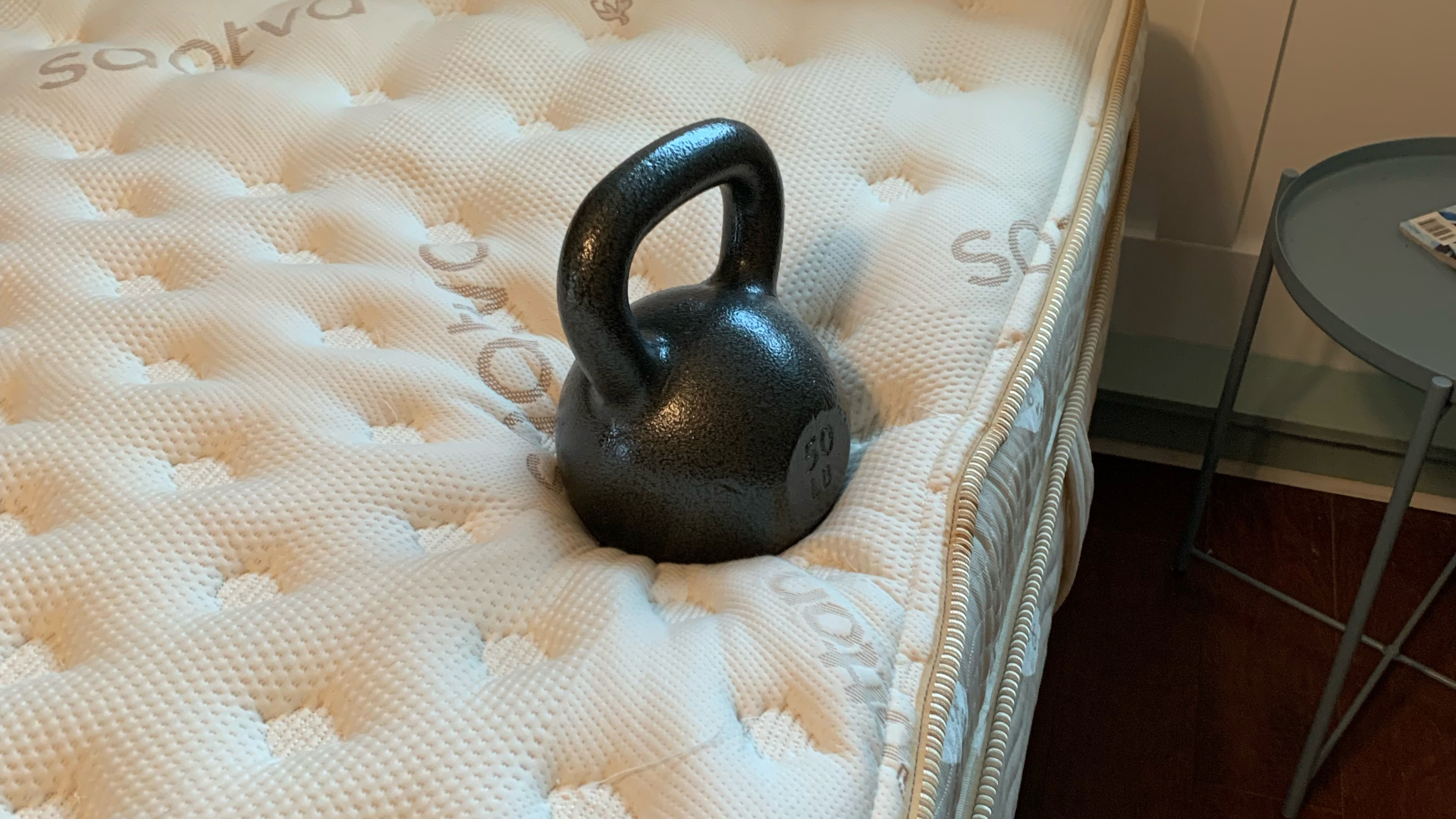 A black kettlebell sat on the edge of the Saatva Classic mattress during testing