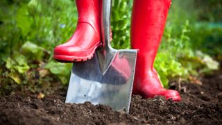 red boots digging with garden spade