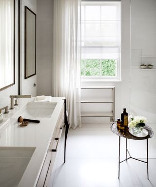 All-white bathroom, marble wall tiles, white painted walls, white floor tiles, metallic side table