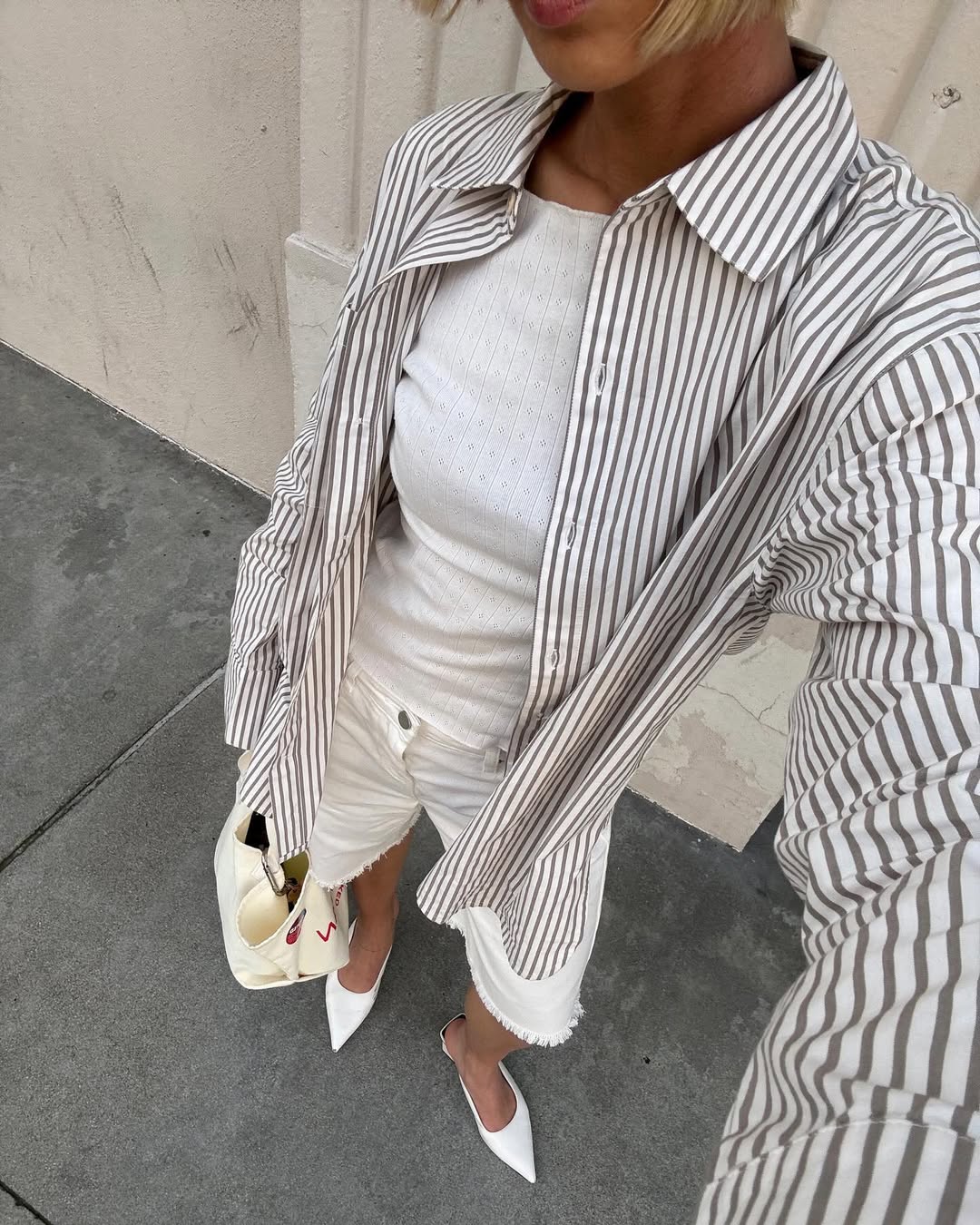 woman wearing white long denim shorts and striped button down shirt