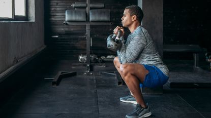 Man holding a kettlebell squat