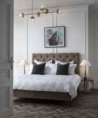 A bedroom furniture idea with upholstered bed, white walls and sputnik chandelier