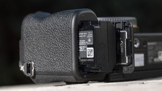 NP-FZ100 battery in the slot of the Sony A7C R camera outside on a wooden table