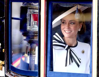 Kate Middleton wearing a white dress with a striped bow smiling from a carriage on Trooping the Colour 2024