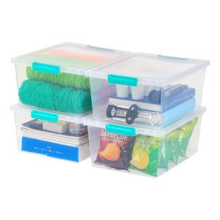 Clear Plastic Storage Bins Containers With Lids and green-blule handles that clip the lids shut. There are four in this image, stacked two by two. Inside are books, papers, snacks and yarn