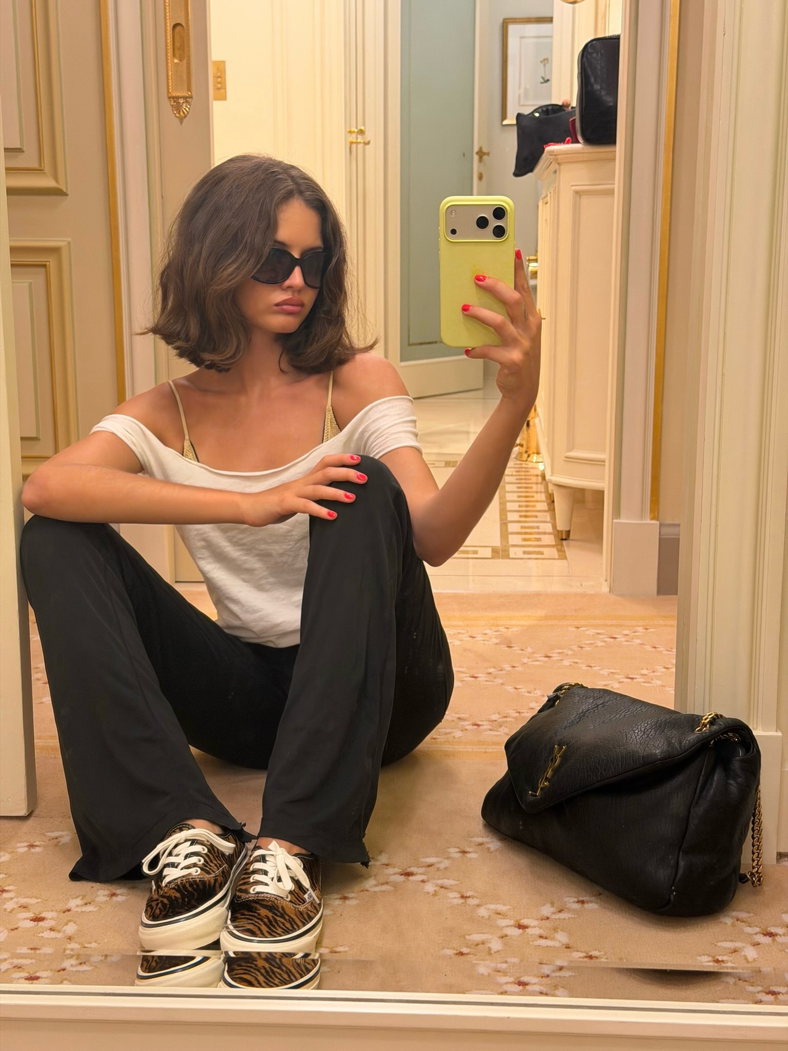 An image of @rubylyn_ wearing a white shirt with black trousers and tiger print trainers from Vans.