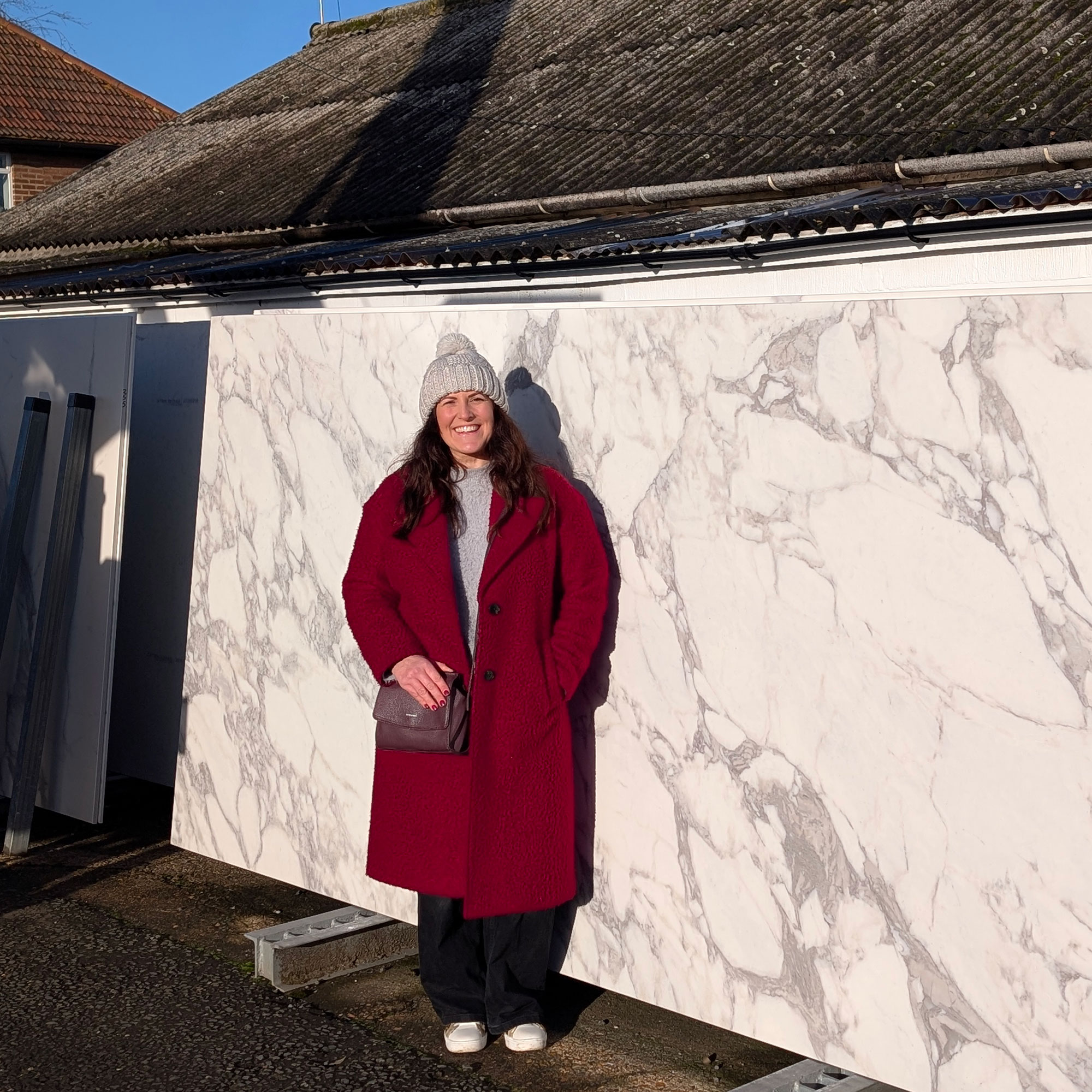 Woman in red coat standing in front of large marble slab