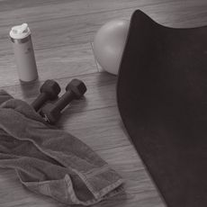 home workout kit on a wooden floor - dumbbells, mat, water bottle, towel, pilates ball