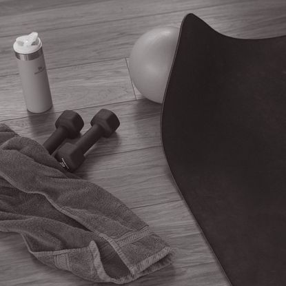 home workout kit on a wooden floor - dumbbells, mat, water bottle, towel, pilates ball