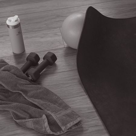 home workout kit on a wooden floor - dumbbells, mat, water bottle, towel, pilates ball