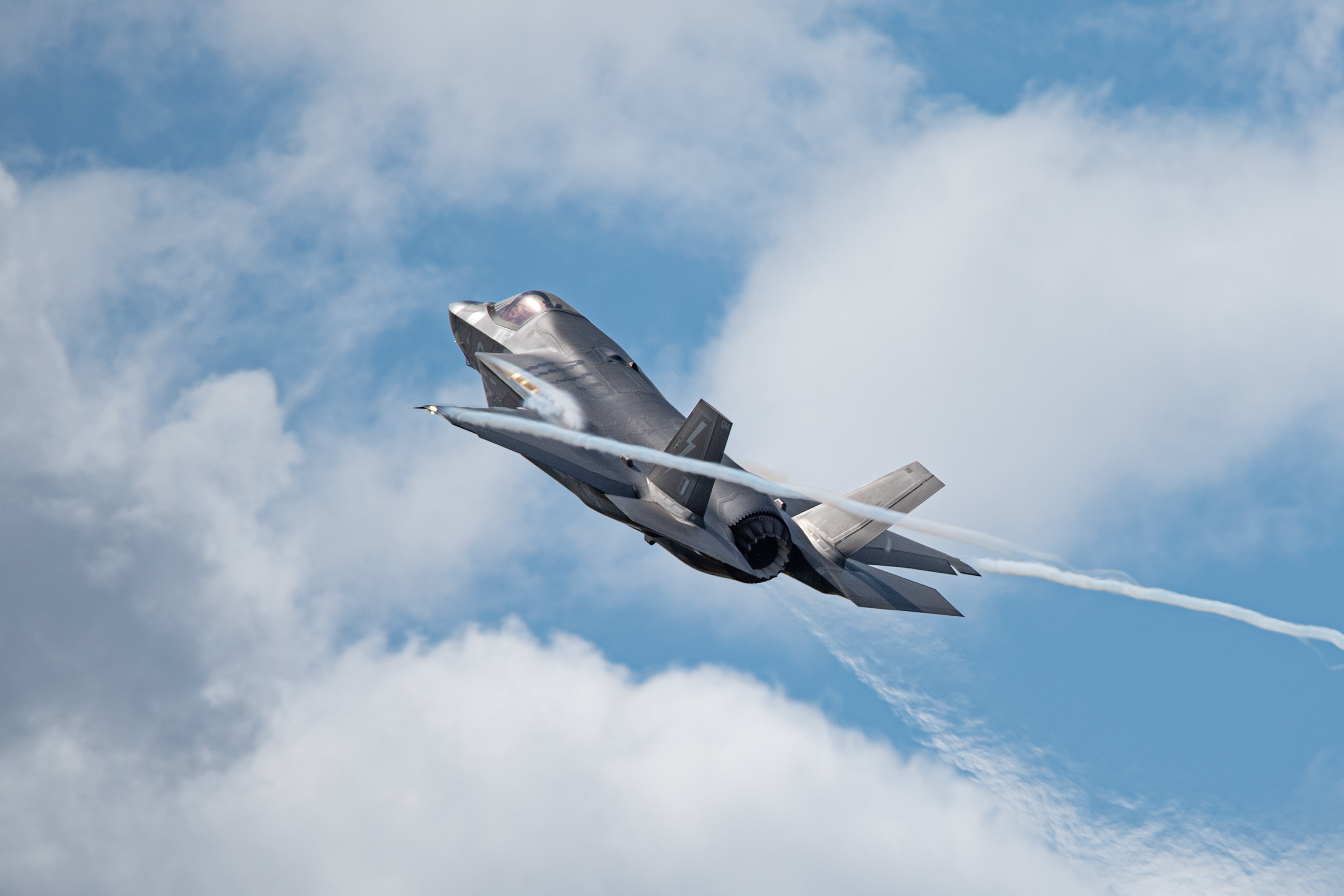 Old Buckenham, UK, July 27 2024: RAF F-35B fighter jet aircraft in flight at the airshow. Climbing fighter jet with vapour trails and heat haze