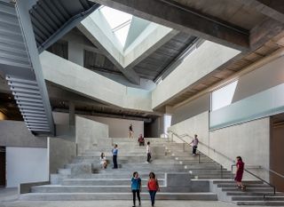 Interior view of the Glassell school of Art featuring a dramatic set of wide steps with people standing and sitting on the staircase