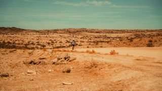 Ultra runner Jon Shield runs across a desert landscape.