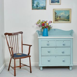room with wooden chair blue vase and drawer