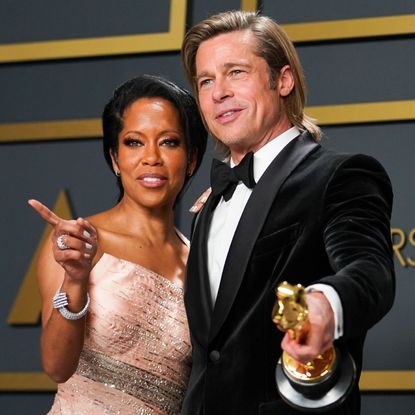 Regina King and Brad Pitt holding his Oscar award.