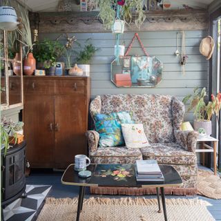 Garden office with vintage sofa, wall panelling, vintage mirror, log burner and hanging planters