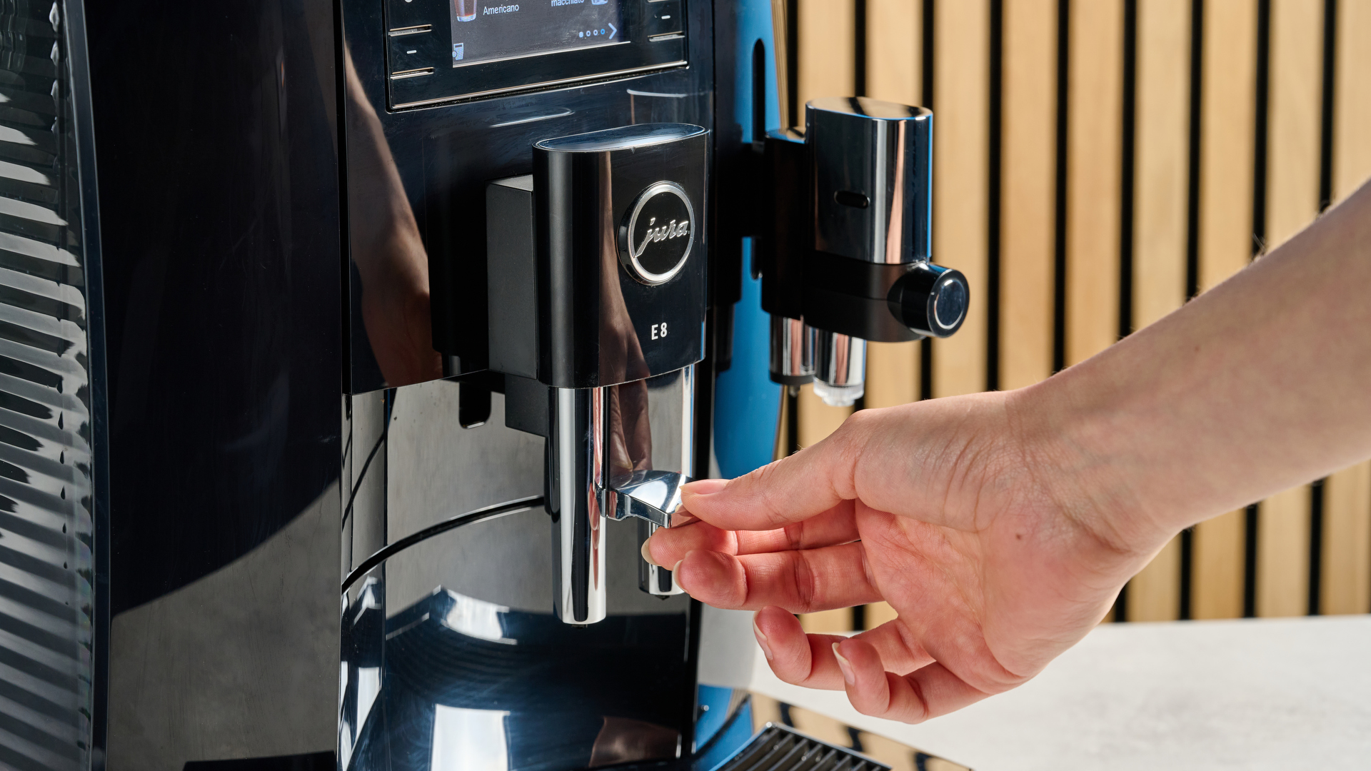 the jura E8 automatic coffee machine in piano black with a 64 ounce water tank, screen, and jura logo on the front