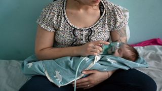 A woman holds an oxygen mask over the face of a baby with Covid-19 in a children's hospital in Kiev.