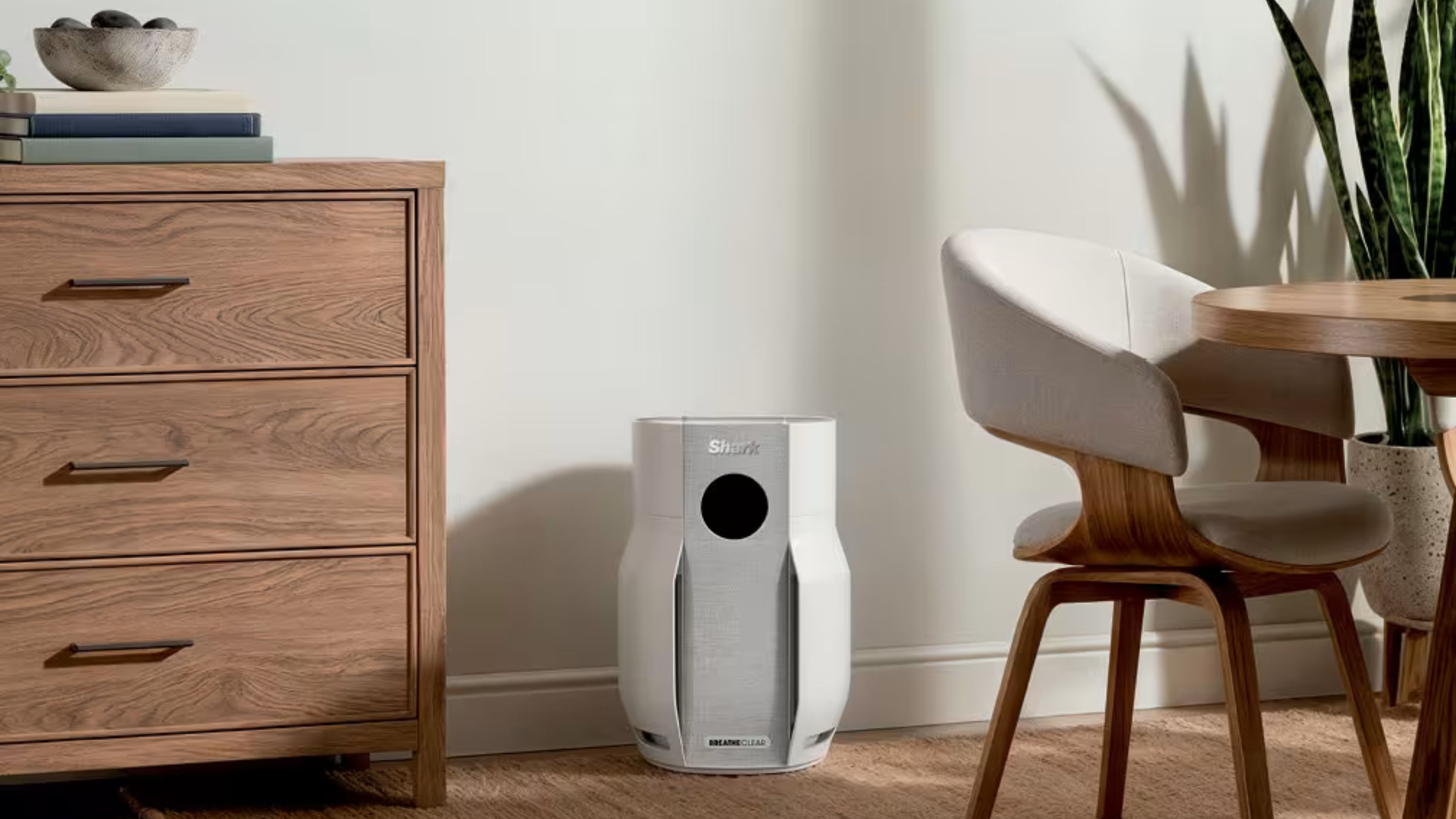 White Shark BreatheClear NeverChange6 Air Purifier sitting on wooden floor in a dining room, next to wooden dining room chairs