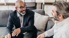 A financial adviser talks with a client on a sofa in his office.
