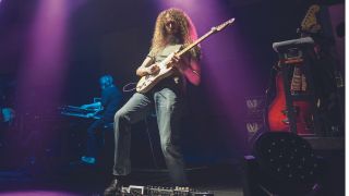 Guthrie Govan plays his signature guitar on stage with a fretwrap on the neck