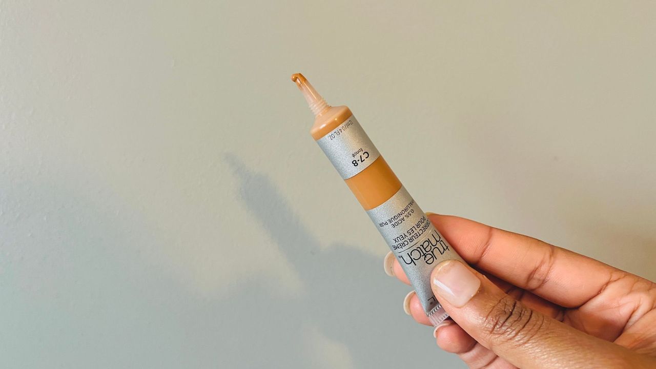 A person holding an opened L'Oreal True Match concealer for the best drugstore concealer.
