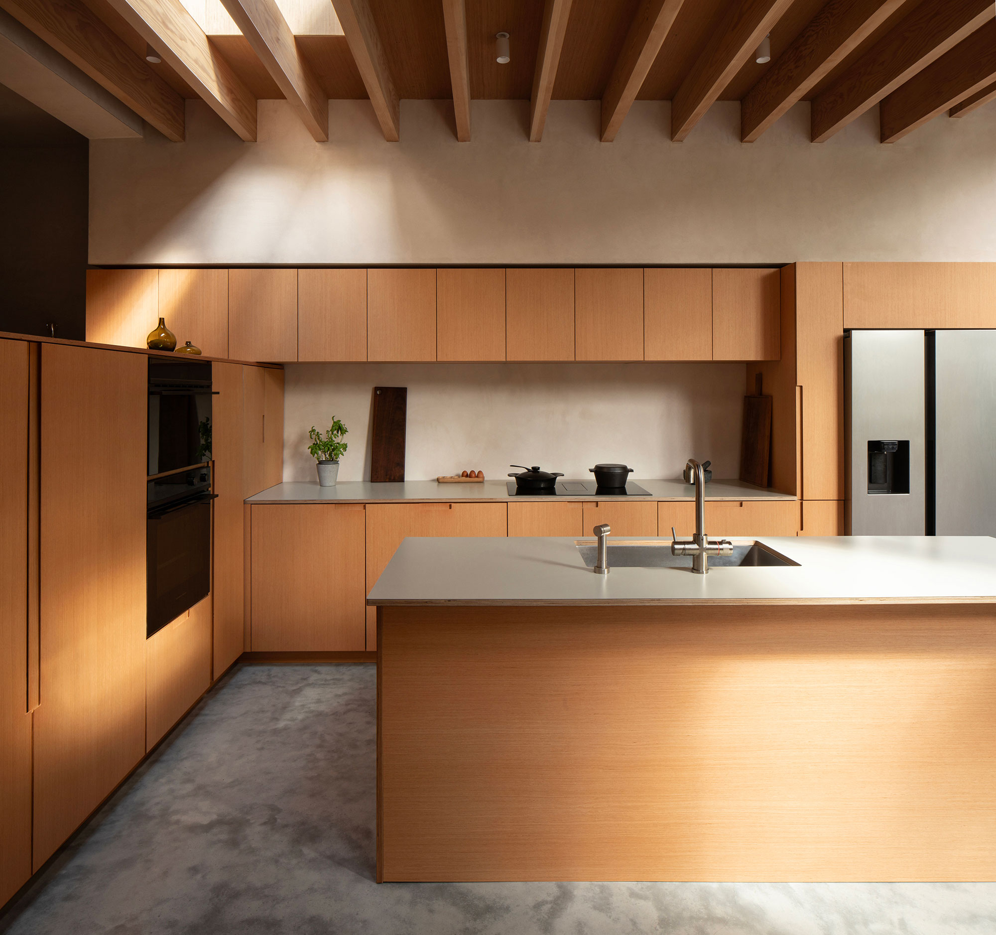 a modern extension with minimalist wood cabinets and a rafter ceiling with a skylight behind