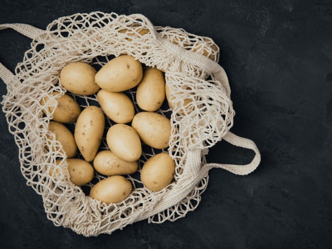 An overhead view of white potatoes in a string bag