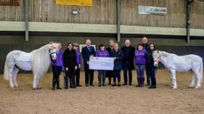 Ponies Alby and Spider look on with some of Unicorn Centre&rsquo;s supported volunteers as (from left) Edmund Levie on behalf of Ferrum Lodge presents the cheque to chair of trustees