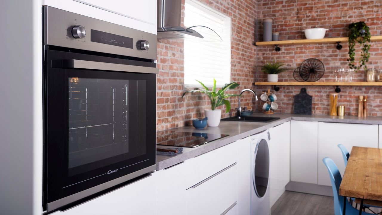 oven in a modern kitchen with red bricks, white cupboards and floating shelves with accessories on them