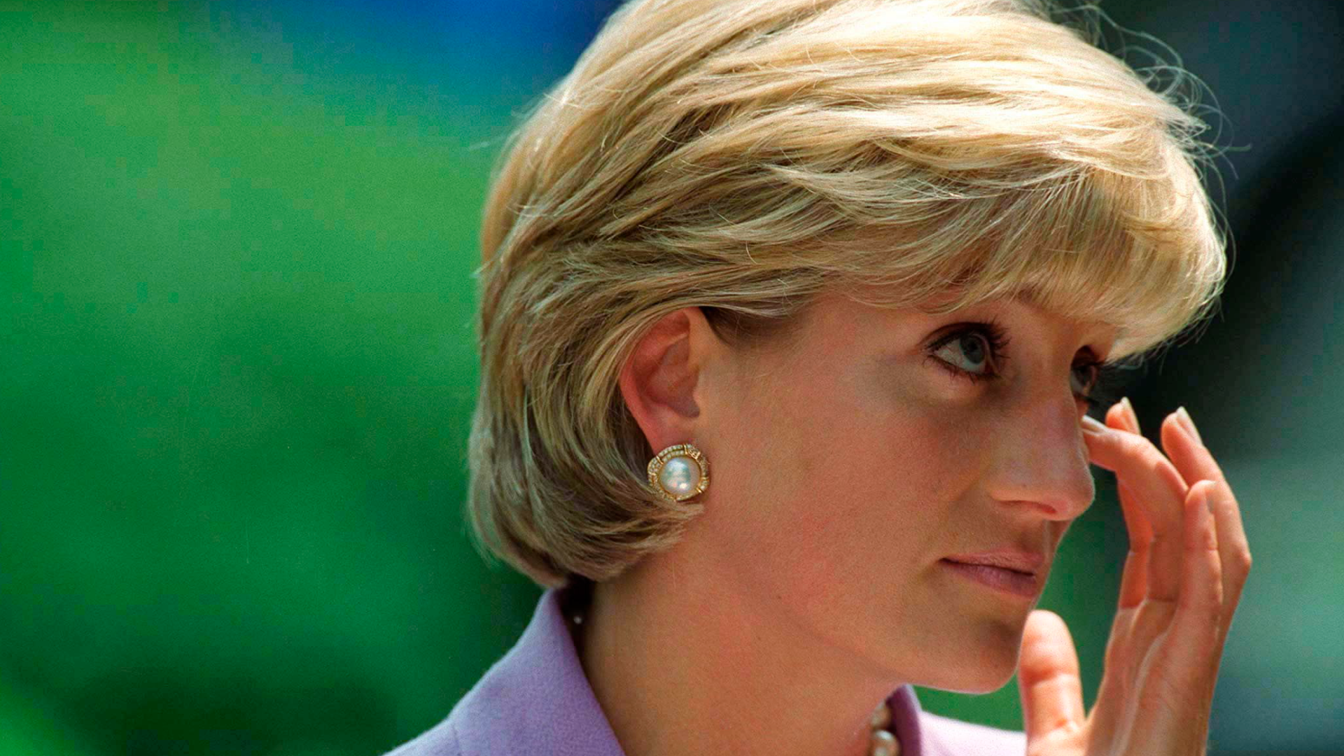 Princess Diana wearing a lavender suit and wiping her eye