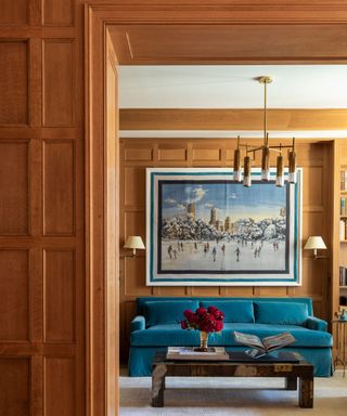 wood paneling doorway and living room with blue couch and large artwork