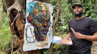 An artist stands in a jungle painting