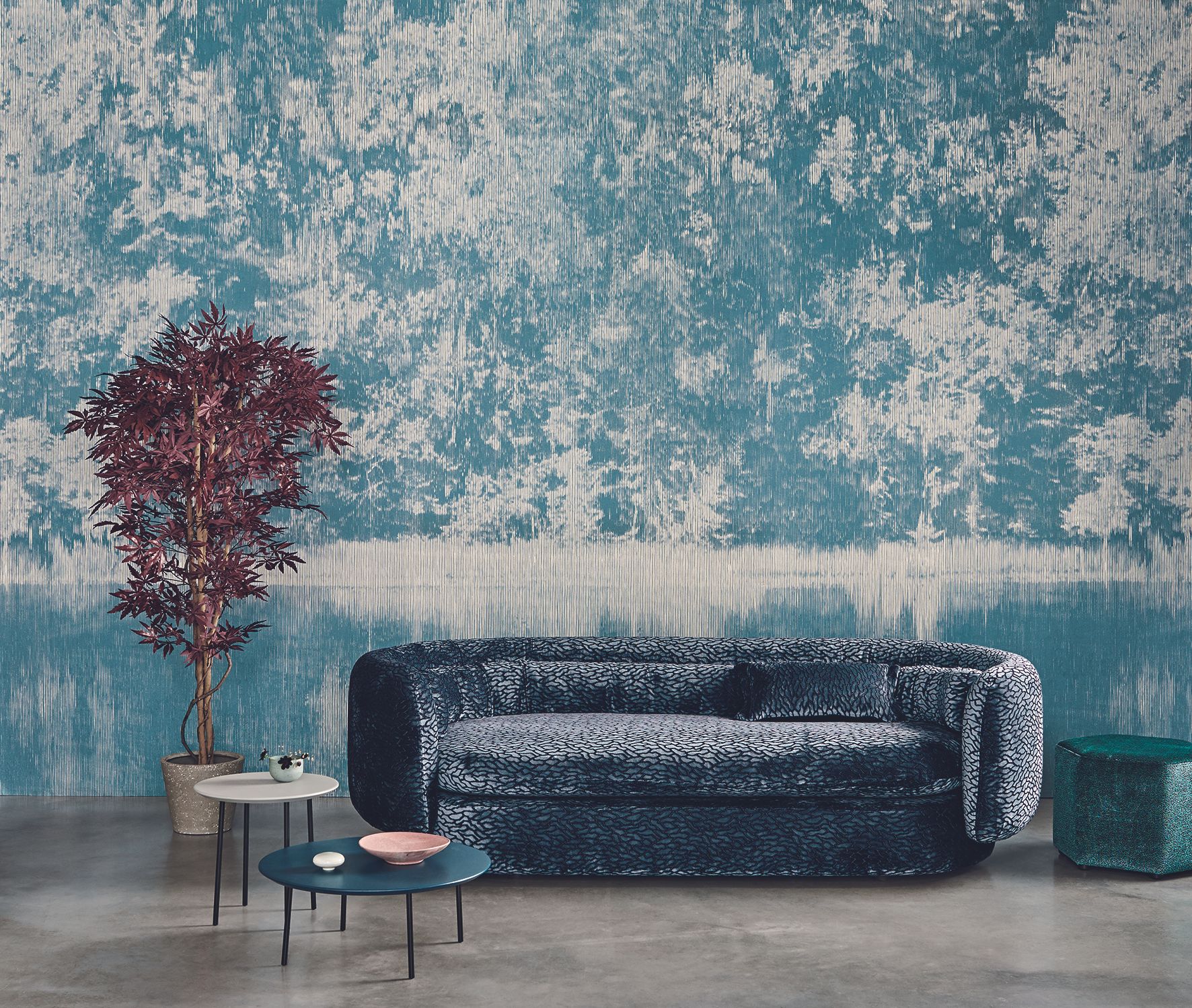 blue wall mural in living room with blue velvet textured sofa, coffee tables, concrete floor