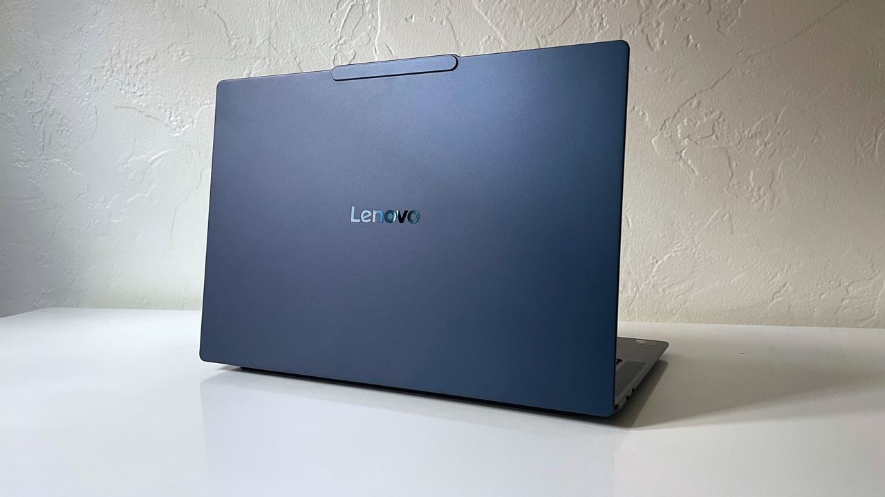 The back of a black laptop sitting on a white desk with the lid open.