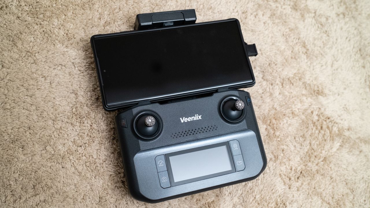 Controller with a phone attached for a Veeniix V11PRO drone on a beige carpet