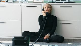 Amanda Seyfried sidder på gulvet med en telefon i en scene fra serien The Dropout