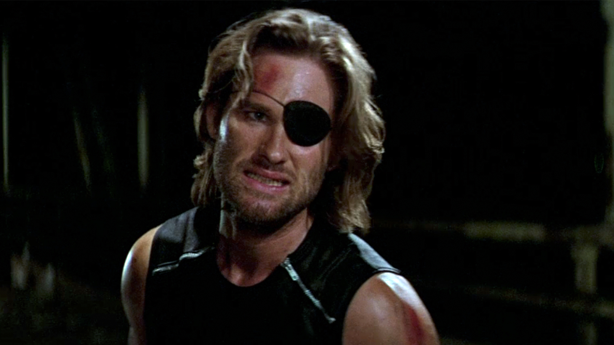 A close up of Kurt Russell looking pained in Escape From New York