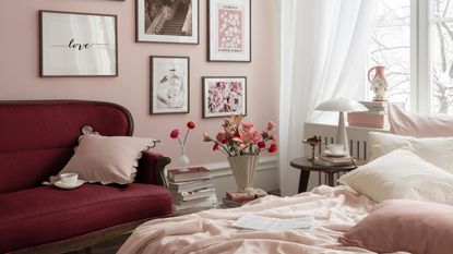 Pink bedroom with a gallery wall of artworks, a purple couch, and a pink bed