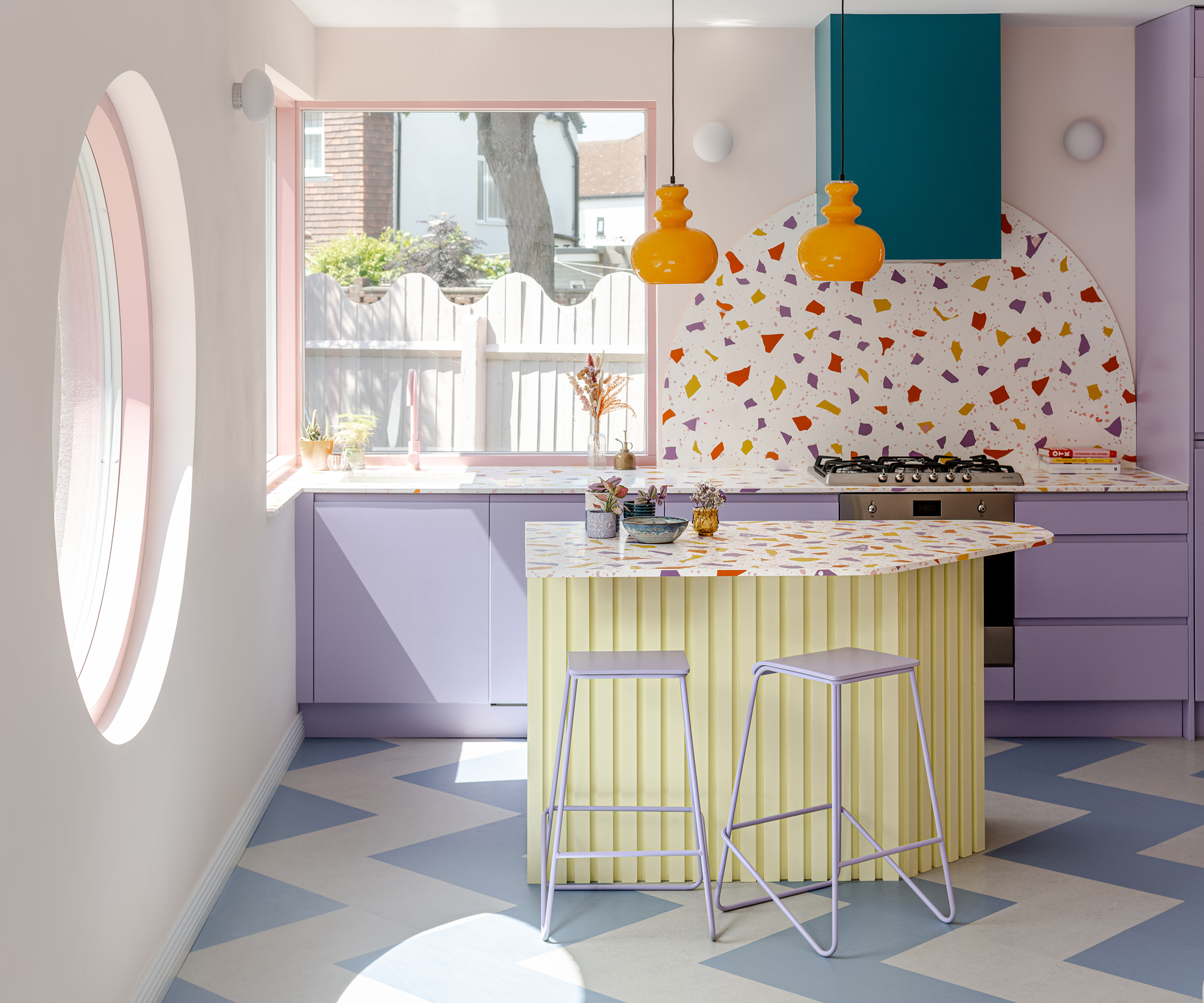 A pastel coloured kitchen with terrazzo kitchen island and backsplash