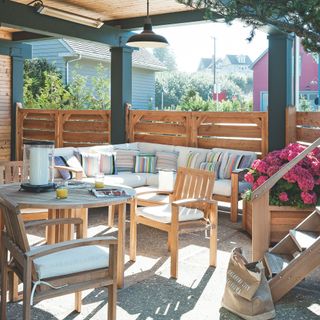 Wooden garden furniture with seat cushions next to wooden fence screen