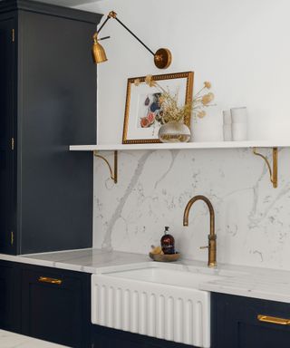 Marble kitchen with dark painted cabinets and brass tap