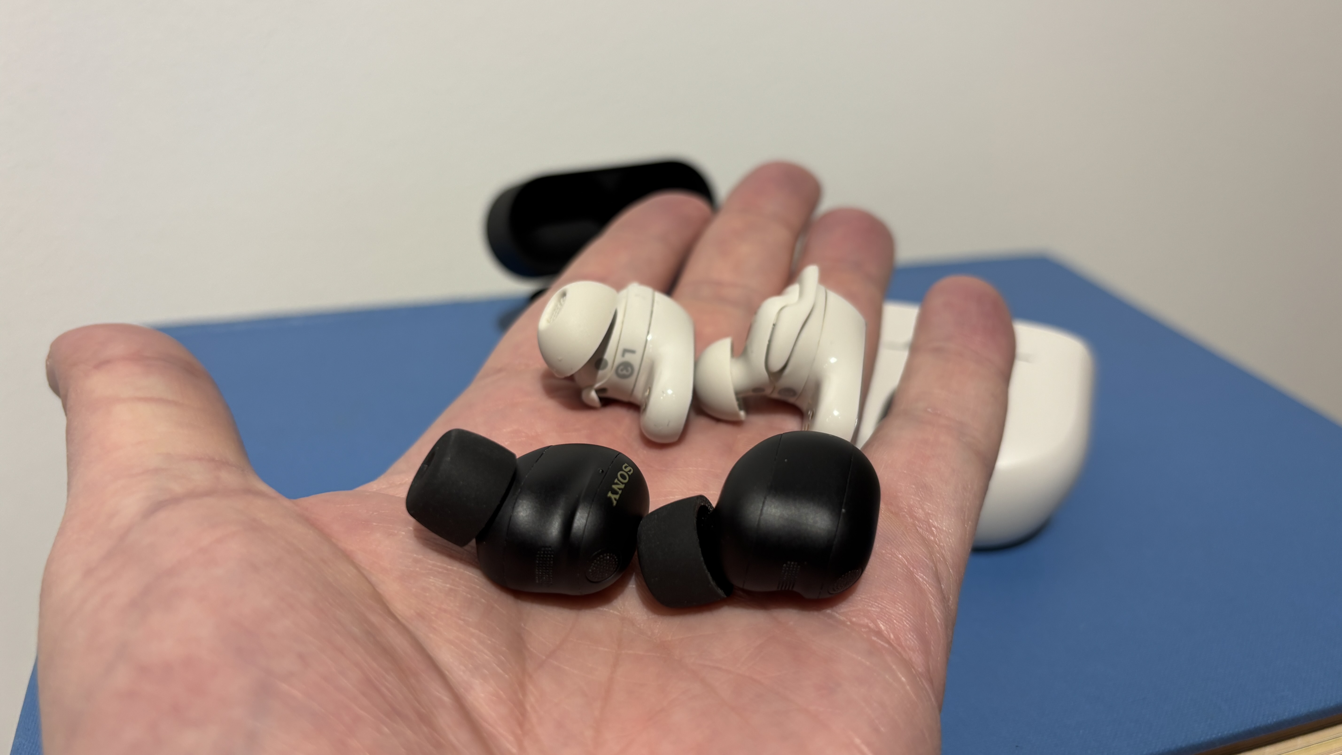 Sony WF-1000XM6 earbuds and Bose QC Ultra Earbuds (2nd Gen) held in the palm of a hand