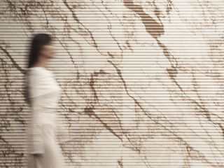 A blurred woman and beige marble wall