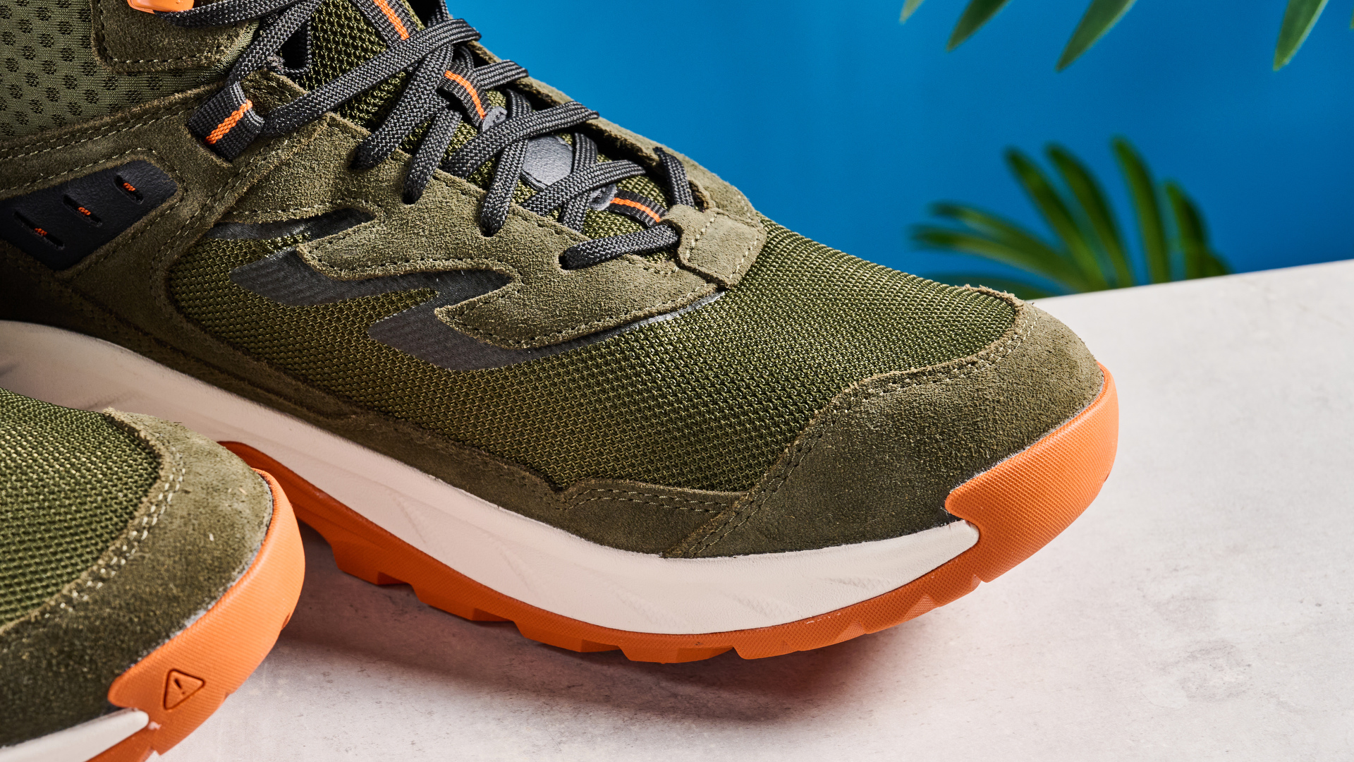 The Keen Hightrail Mid boots in Green on a stone surface against a blue background