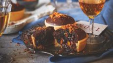 Two chocolate coffee brownie mince pies on a table with another that has a bite taken out of it.