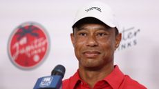 Tiger Woods speaks to the media at TGL wearing a white cap and red polo