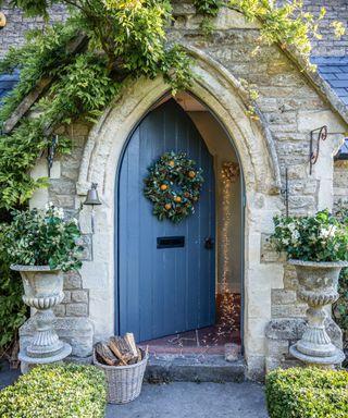 gothic style front door dressed for christmas with a wreath and lights