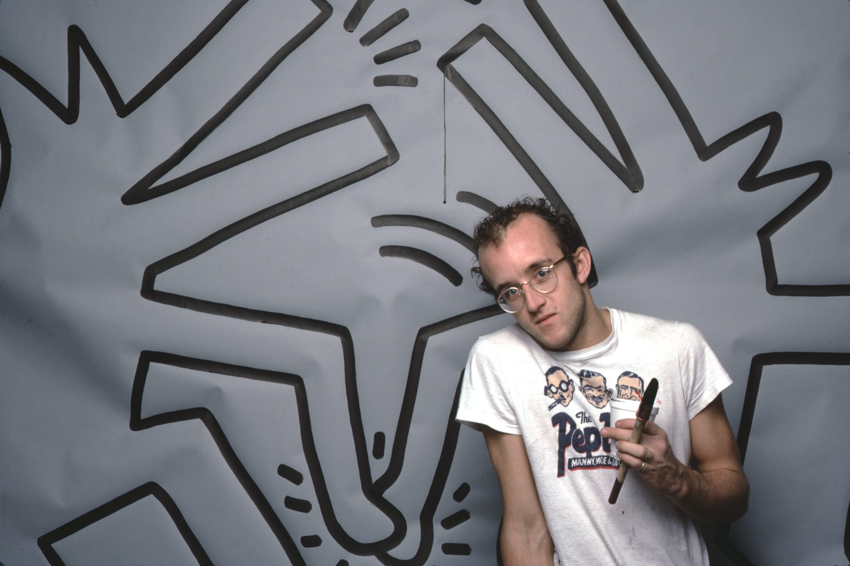 Graffiti and visual artist Keith Haring photographed with one of his paintings in April 1984. Photo by Jack Mitchell/Getty Images.