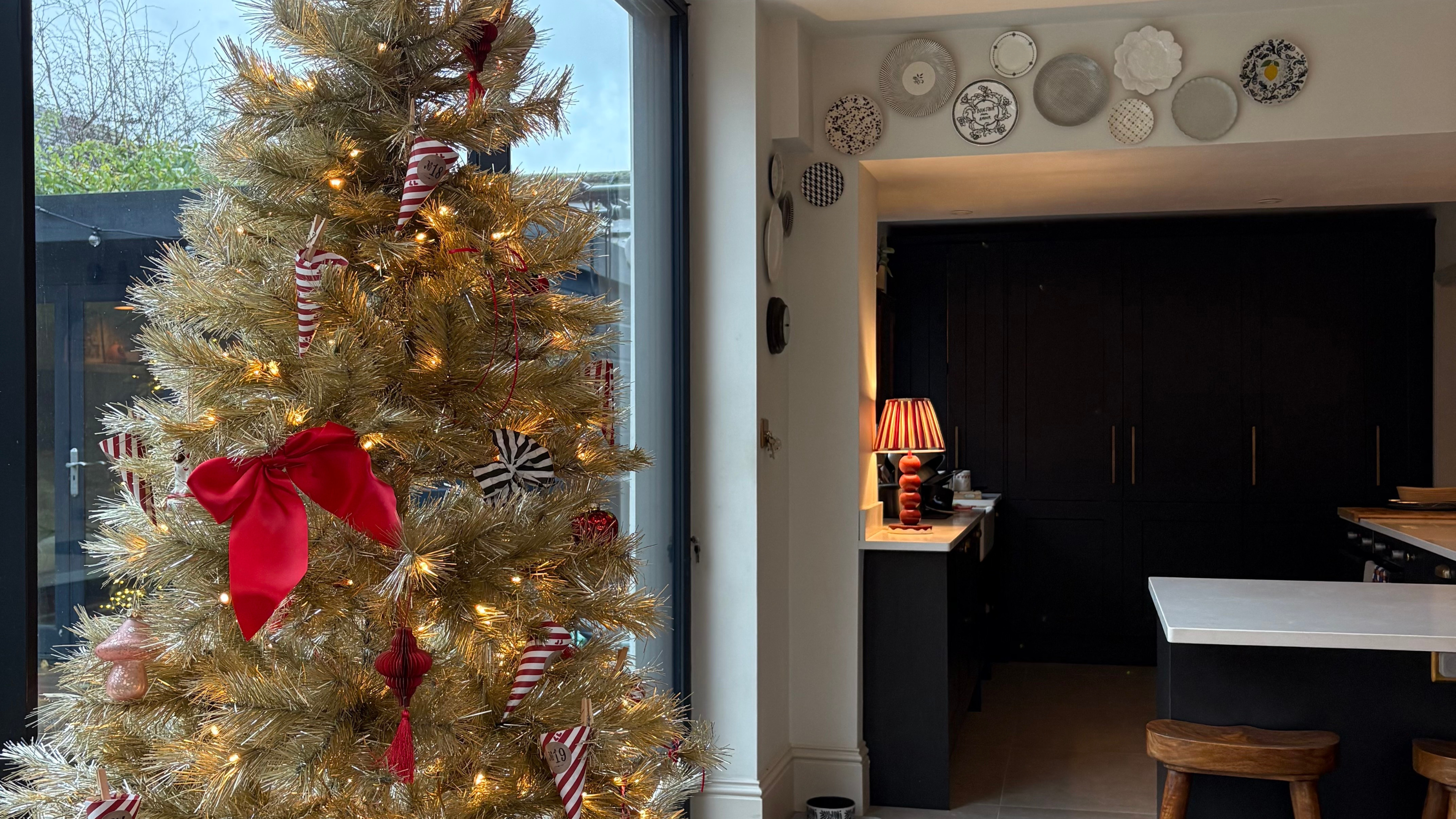 Close-up of Heather&#039;s gold tree adroned with red bows, striped baubles and food themed decorations.